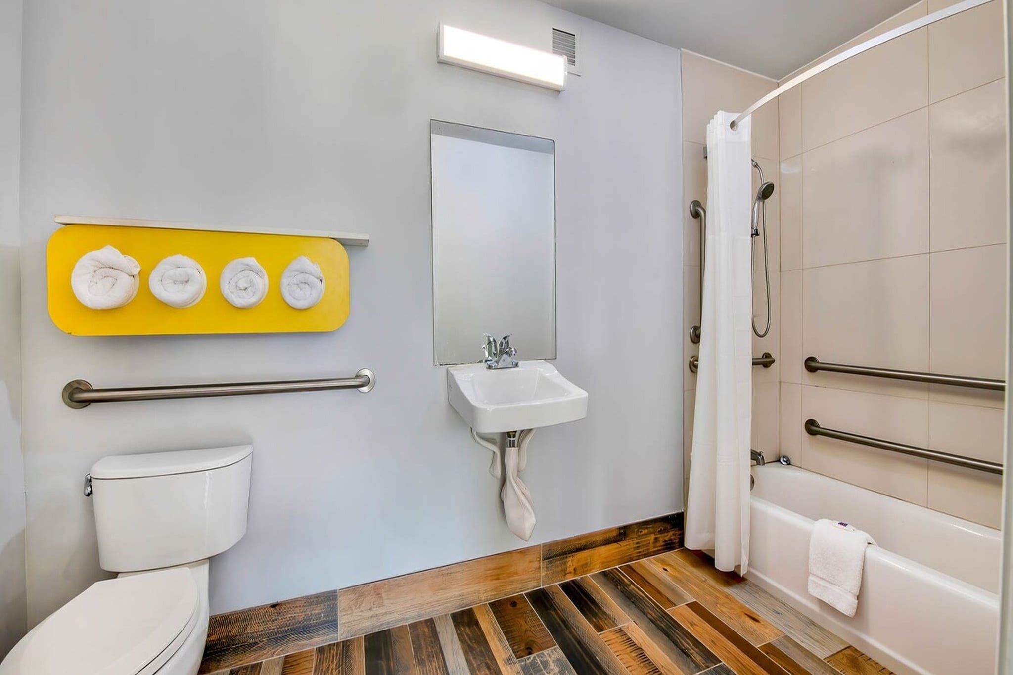 Ein Badezimmer mit Toilette, Waschbecken, Dusche und einem gelben Handtuchhalter.