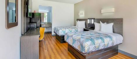 Una habitación de hotel con cama, mesitas de noche, escritorio, silla y kitchenette.