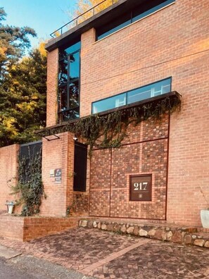 A brick building with a large window and a sign displaying the number 217. - studio21 seven (Pretoria)
