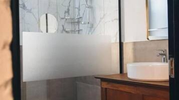 A bathroom with a marble wall, a wooden vanity, and a mirror.