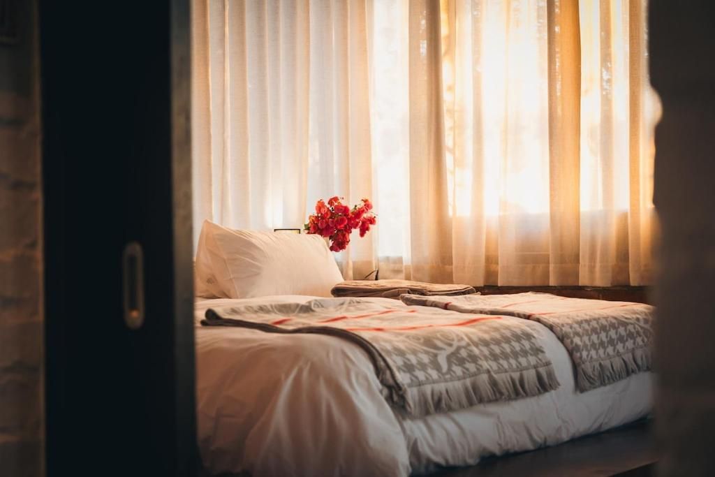 Un dormitori amb un llit, una tauleta de nit i un ram de flors.