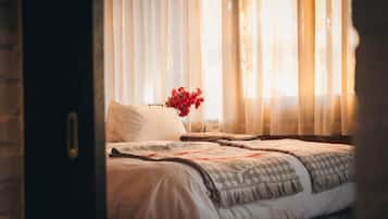 A bedroom with a bed, a nightstand, and a vase of flowers.