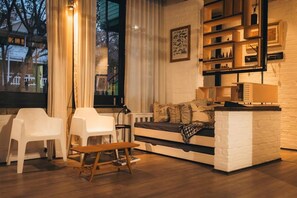 A cozy living room with a sofa, two white chairs, a wooden bench, and a bookshelf.