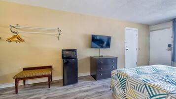 A bedroom with a bed, a TV, a bench, a dresser, and a wardrobe.