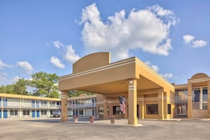 Um motel com área de estacionamento coberta, vários quartos e a bandeira americana.