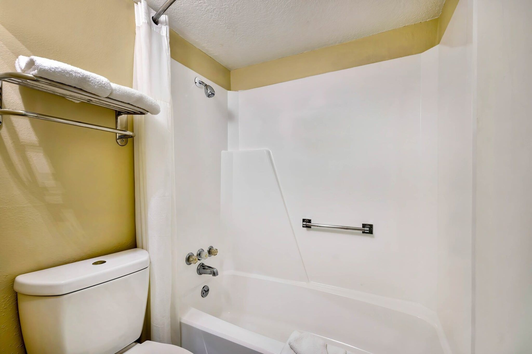 Et badeværelse med toilet, bruser og badekar.