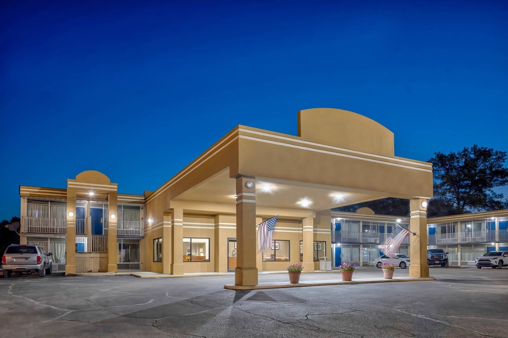 A hotel with a covered entrance, multiple floors, and a parking lot.