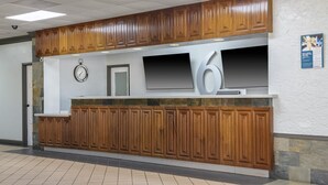 Zona de recepció amb un panell de fusta, un rellotge, un televisor de pantalla plana i un senyal gran amb el número 6.