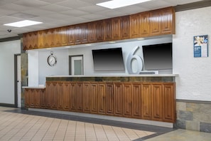 A reception area with a wooden panel design, a clock, a flat-screen TV, and a large number '6' sign. - 1 King Bed | Smoking, Kitchen (Stockbridge GA)