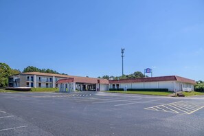 Un motel con varias habitaciones, un estacionamiento y cielo despejado.