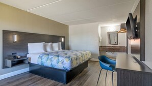 Habitació d'hotel amb llit, taula de nit, escriptori, cadira i televisió penjada a la paret.