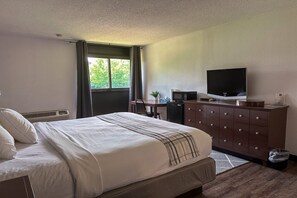 A hotel room with a bed, a desk with a computer, a television, and a dresser. - 1 King Bed | Mobil Access Tub Nsmk Micfridg (Rochester NY)