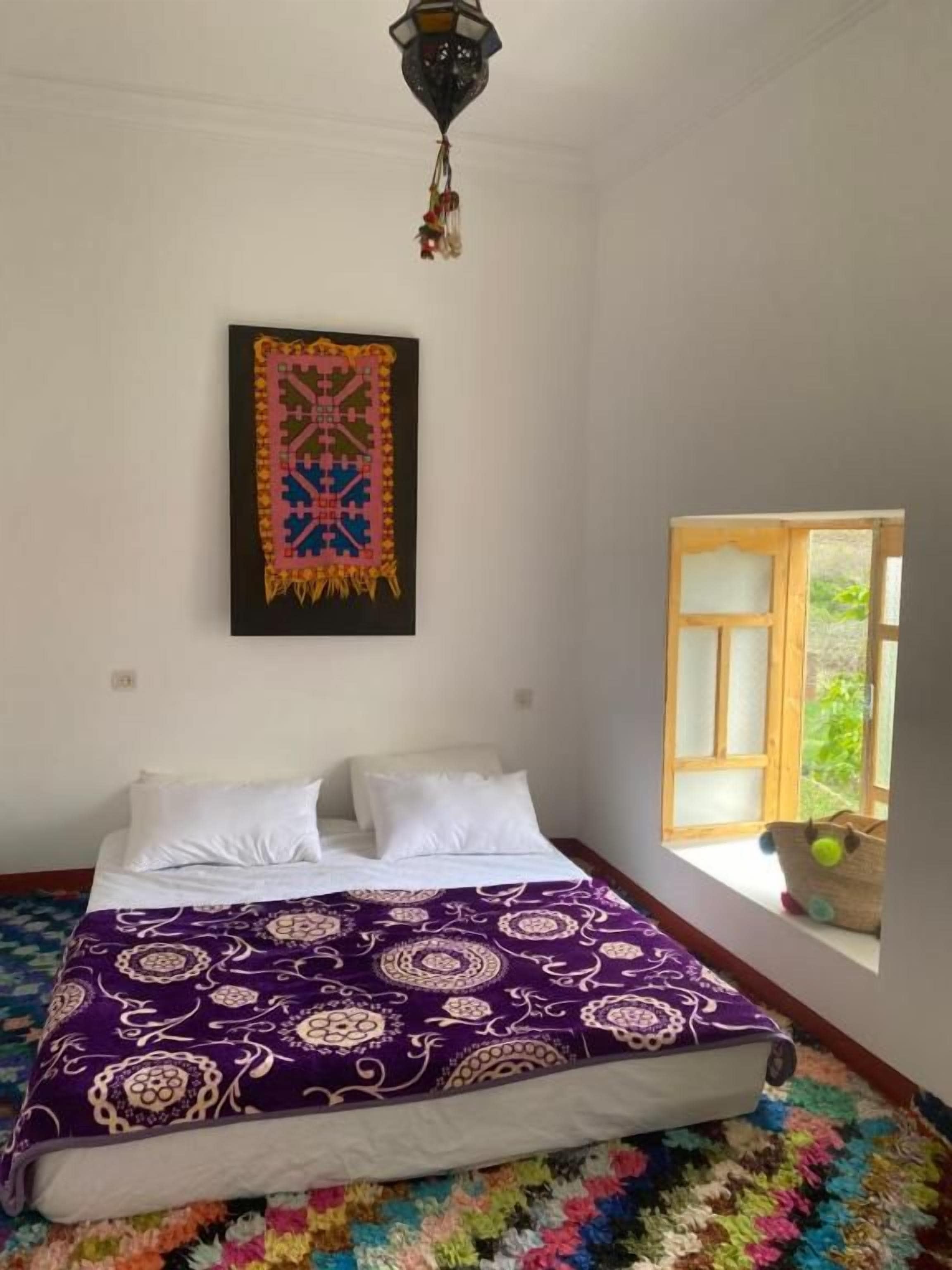 Ein Schlafzimmer mit einem Bett, einem Fenster und einem Wandbild.