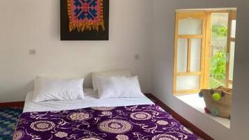 Ein Schlafzimmer mit einem Bett, einem Fenster und einem Wandbild.