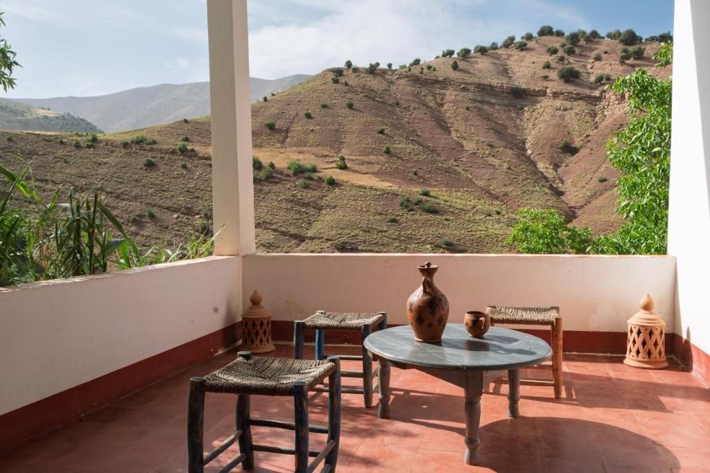 Una terraza con una mesa, sillas y vistas a un paisaje montañoso.