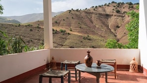 A terrace with a table, chairs, and a view of a hilly landscape. - aubrege sremt (Sremt)