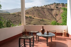 Terrassa amb taula, cadires i vista cap a un paisatge amb turons.
