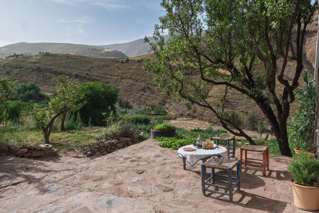 Une terrasse avec un sol en pierre, une table avec des chaises et des plantes en pot.