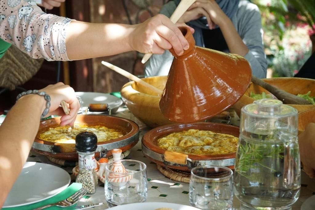 Um grupo de pessoas à mesa de jantar, com diversos pratos e uma grande panela de barro.