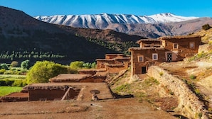 A traditional village with adobe houses, a stone wall, and a mountain range in the background. - aubrege sremt (Sremt)