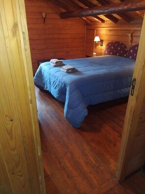 A wooden cabin room with a bed, a nightstand, and a lamp.
