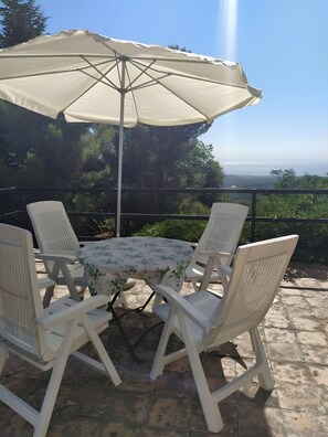 A patio with a table and chairs, an umbrella, and a view of the landscape.