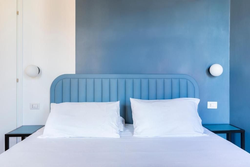 A bed with a blue headboard in a room with a blue accent wall.