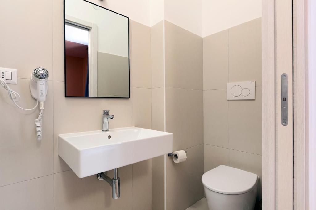 A bathroom with a white sink, a mirror, a hair dryer, and a toilet.