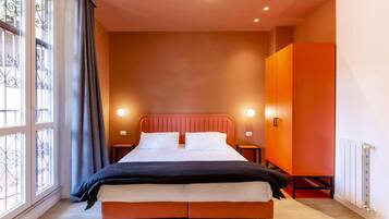 A bedroom with a bed, two bedside tables, and a window with curtains.