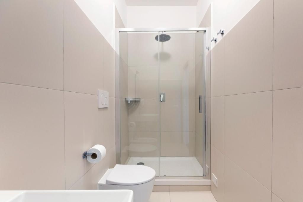 A modern bathroom with a glass-enclosed shower, a toilet, and a sink.