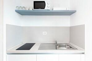 A kitchen with a microwave, a sink, and a countertop. - Luciano San Giovanni Guest House (Rome)
