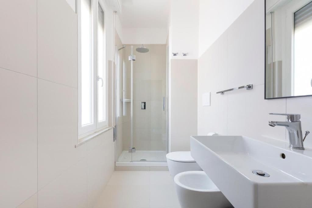 A modern bathroom with a glass-enclosed shower, a white sink, and a large mirror.
