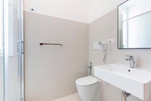 Un baño moderno con inodoro, lavabo y cabina de ducha de vidrio.