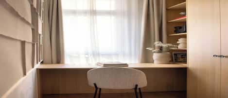 Una habitación con escritorio, silla y ventana con cortinas.