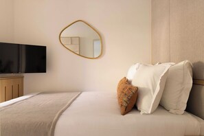 Ein Hotelzimmer mit einem Bett, einem Fernseher, einem Spiegel und einem Holzschrank.