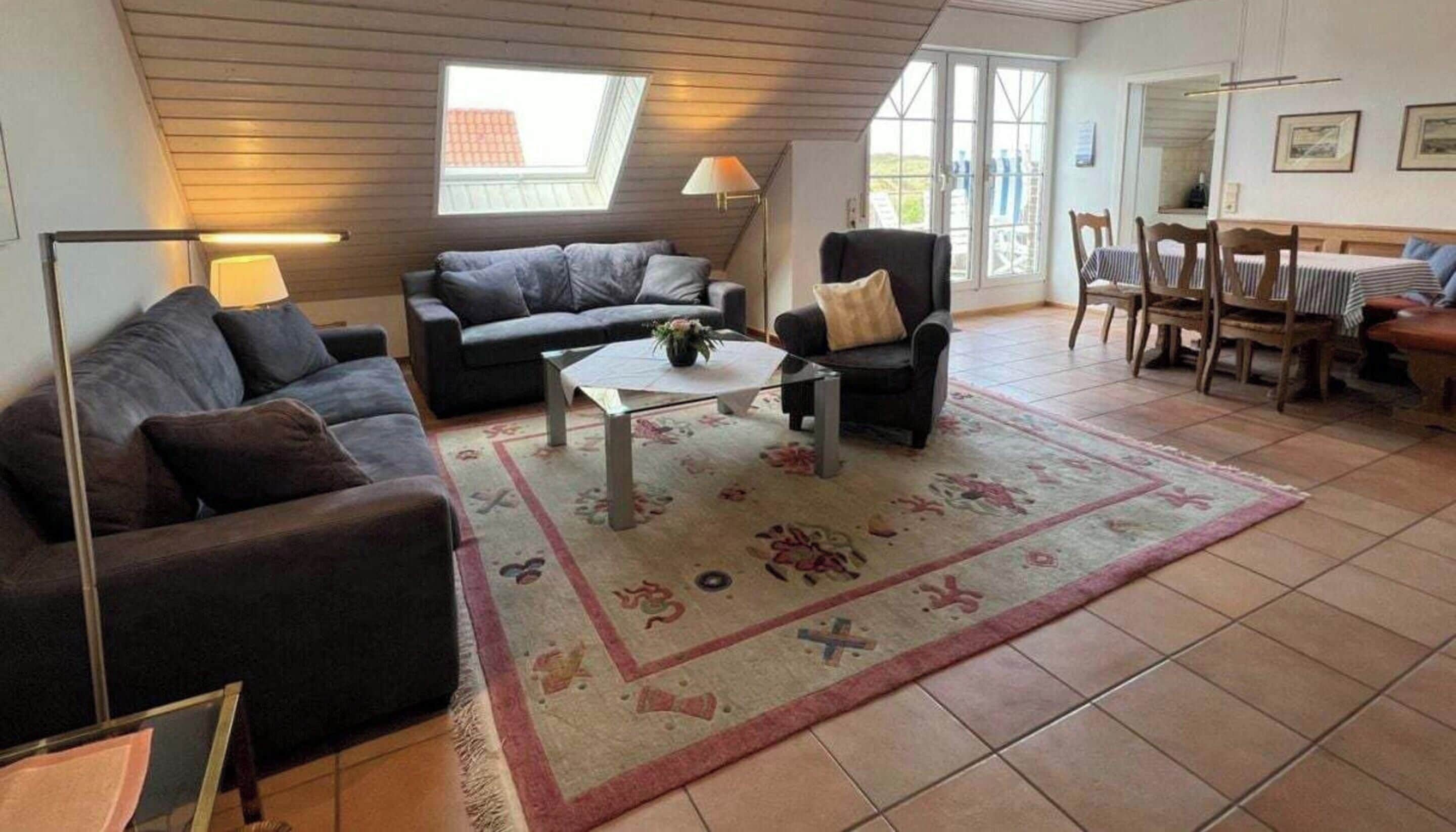 Un salon confortable avec un canapé, un fauteuil, une table basse et un coin repas comprenant des chaises et une table.