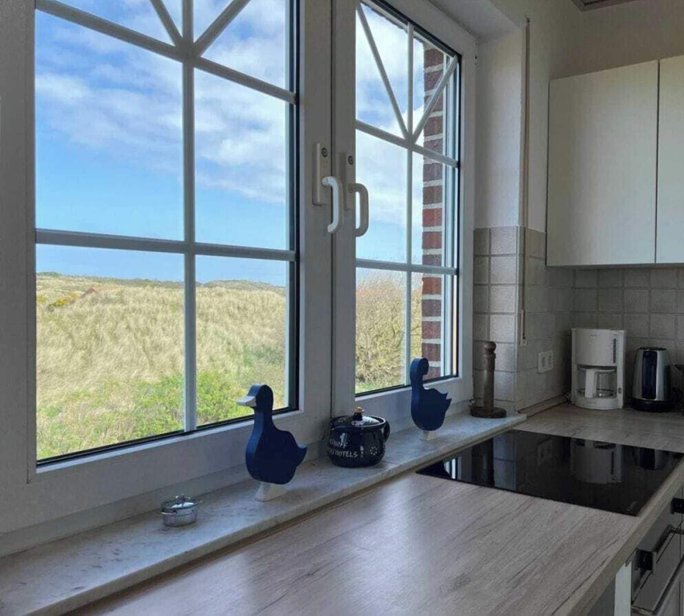 Eine Küche mit einem großen Fenster, einer Kaffeemaschine und einem Wasserkocher auf der Arbeitsfläche.