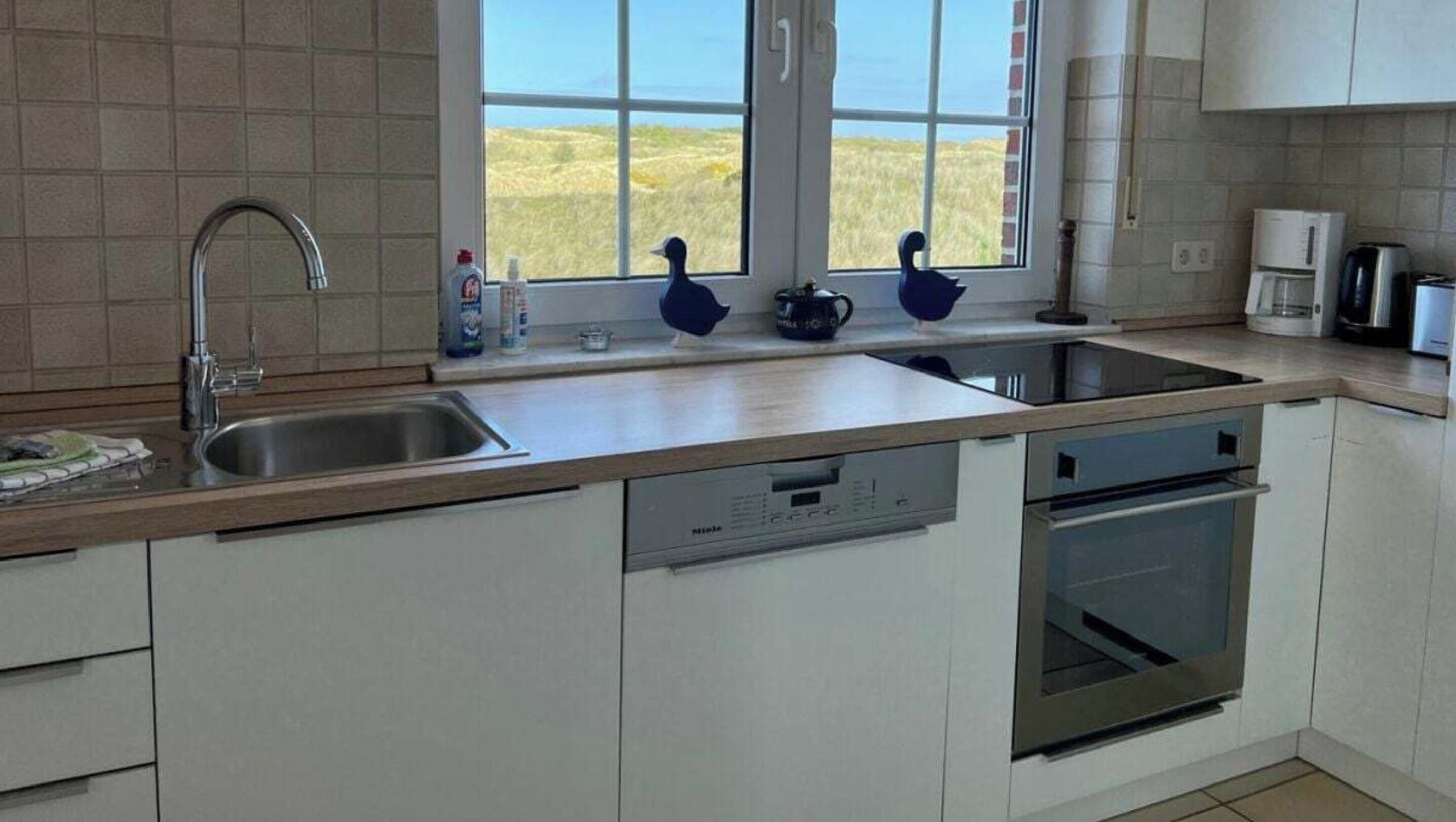 A modern kitchen with a large window, stainless steel appliances, and a dishwasher.