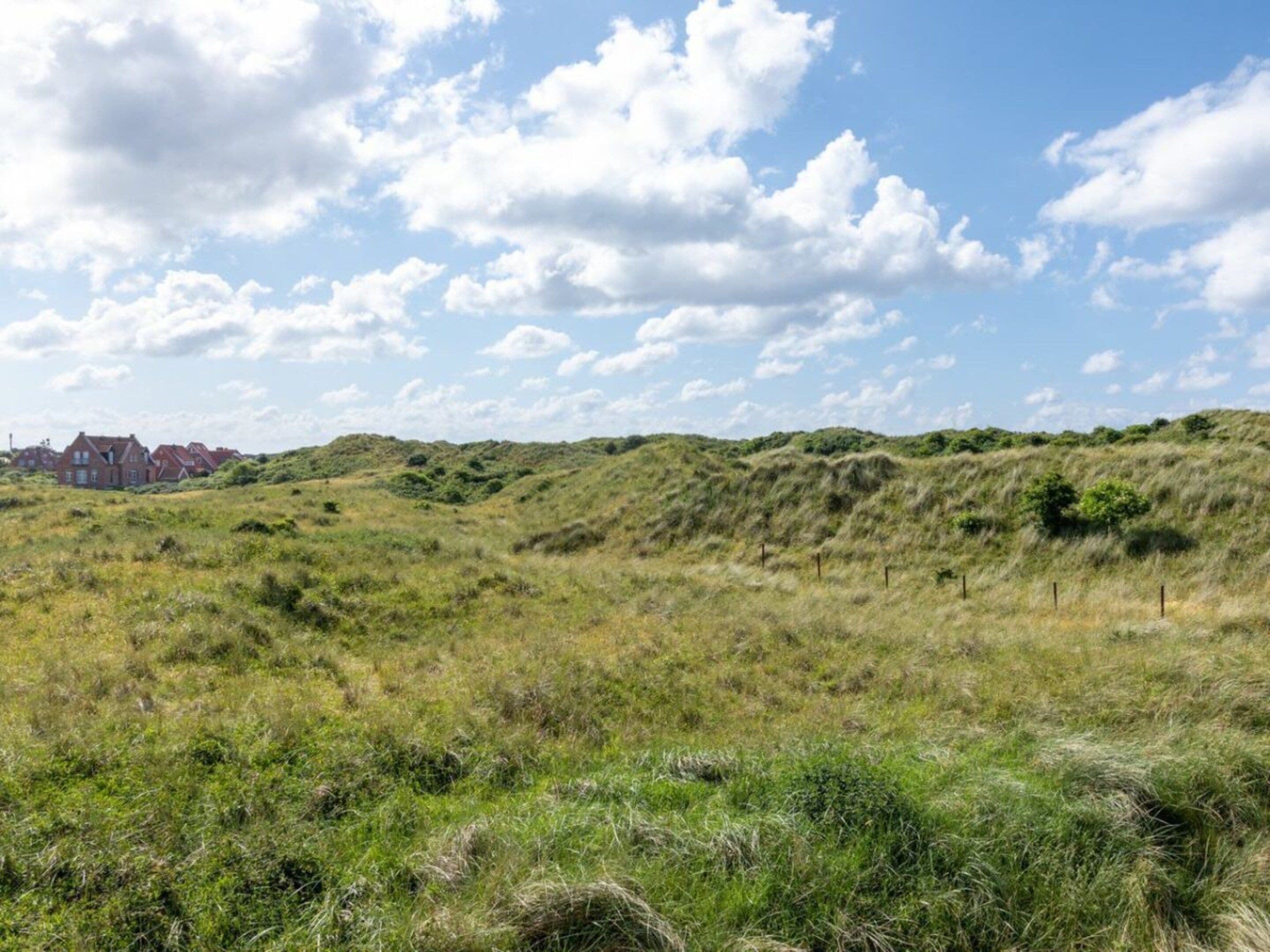 A grassy field with rolling hills and a clear sky.