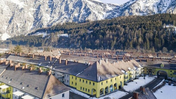 Un paysage montagneux aux sommets enneigés et une ville à l’architecture traditionnelle.