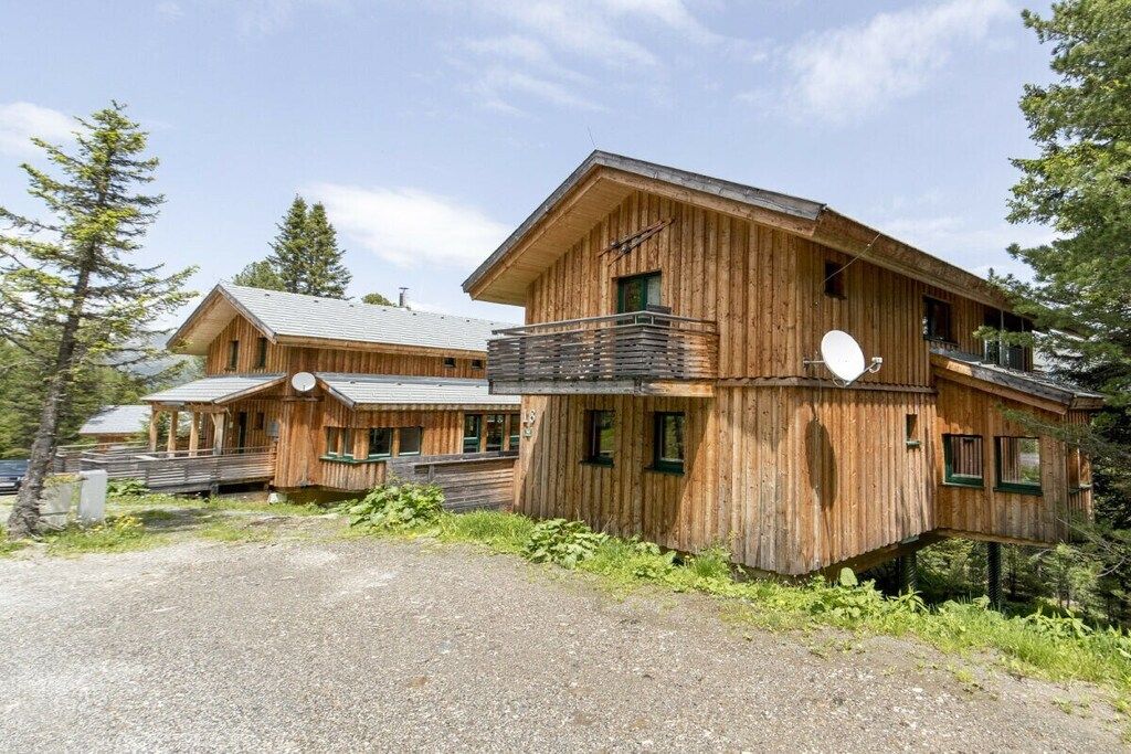 A wooden cabin with a balcony and a satellite dish.