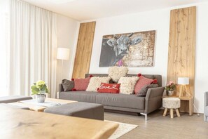 Ein modernes Wohnzimmer mit einem grauen Sofa, einem Couchtisch, einer Lampe und einem Bild an der Wand.