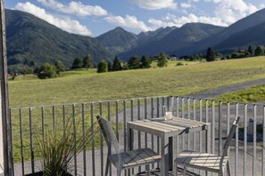 Ein Balkon mit Tisch und Stühlen mit Blick auf eine gebirgige Landschaft.
