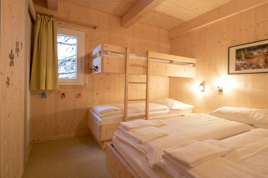 Una habitación de cabaña de madera con literas, una ventana con vistas y una lámpara fijada a la pared.