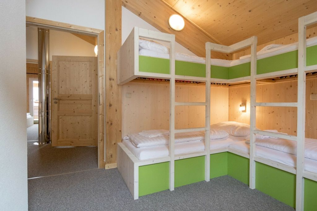 Une pièce avec des lits superposés, une porte en bois et un luminaire.