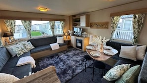 A cozy interior with a sofa set, a dining table, and a kitchen area.