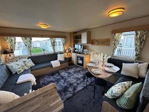 A cozy interior with a sofa set, a dining table, and a kitchen area.