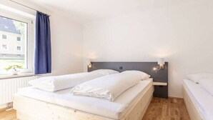 Ein Schlafzimmer mit Doppelbett, einem Fenster mit Vorhängen und einer Wandleuchte.
