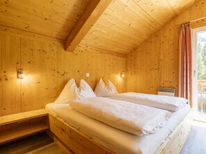 A wooden cabin room with a bed, a window with curtains, and a wall-mounted light fixture. - Cabin in Annaberg With Swimming Pool (Annaberg-Lungoetz)