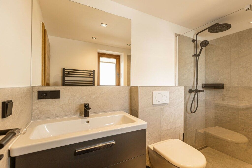 A modern bathroom with a sink, toilet, and shower.